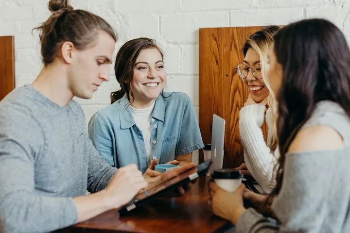 Three people talking around a table with a laptop